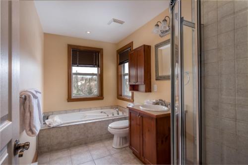 a bathroom with a tub and a toilet and a sink at Aiglon by Rendez-Vous Mont-Tremblant in Mont-Tremblant