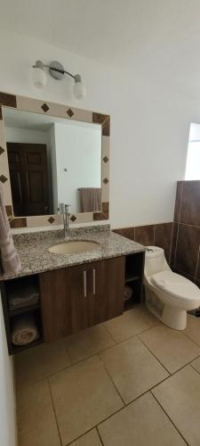 a bathroom with a sink and a toilet and a mirror at Villas Eco Development in Playa Junquillal