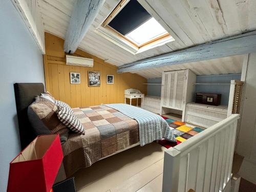 - une chambre mansardée avec un lit et une lucarne dans l'établissement UN MOMENT SUSPENDU, à Aix-en-Provence