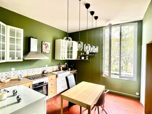 uma cozinha com paredes verdes e uma mesa de madeira em UN MOMENT SUSPENDU em Aix-en-Provence