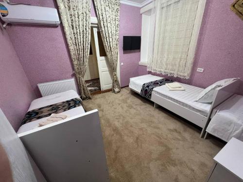two beds in a room with purple walls at Guest House Han in Samarkand