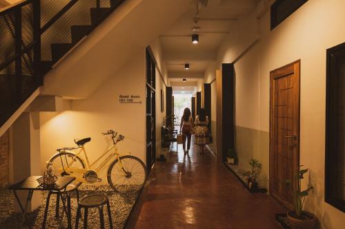 Ban Laem Muang的住宿－Sirichai Design Hotel，一辆自行车停在走廊上,一名妇女沿着走廊走