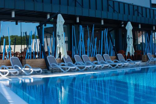 a row of chairs next to a swimming pool at Hotel Aventus in Baile Felix