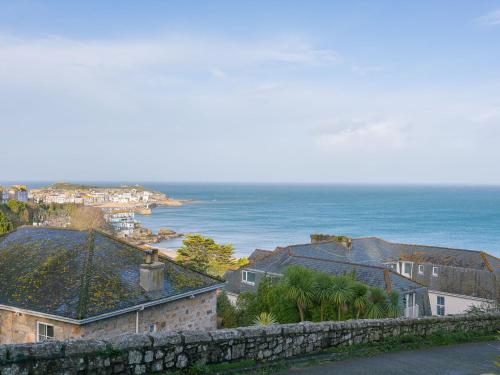 a view of the ocean with houses and a stone wall at Godrevy Shepherds Hut in Hayle
