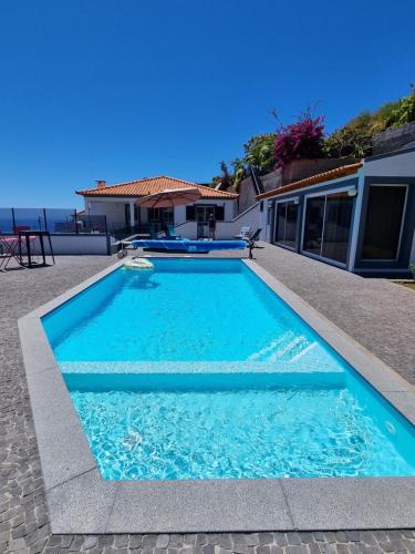 a swimming pool in front of a house at Casa agapanthe in Estreito da Calheta