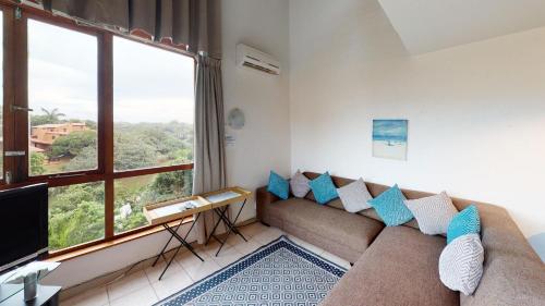 ein Wohnzimmer mit Couch und großem Fenster in der Unterkunft San Lameer Villa 1916 by Top Destinations Rentals in Southbroom