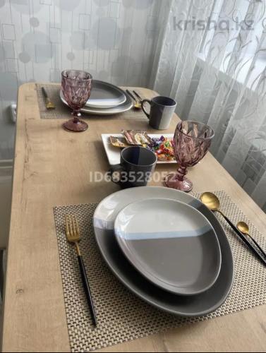 a table with plates and silverware on top of it at Комфортабельные - уютные апартаменты в Костанай мкр Юбилейный in Kostanay