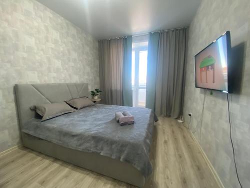 1 dormitorio con 1 cama y TV en la pared en Комфортабельные - уютные апартаменты в Костанай мкр Юбилейный en Kostanái