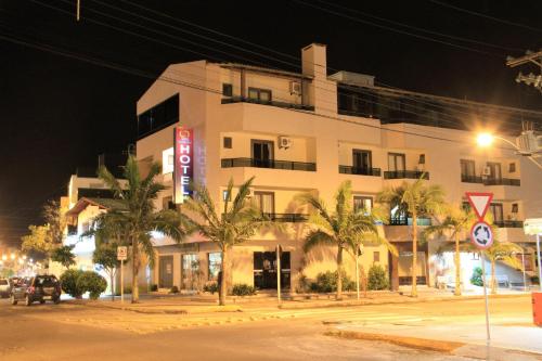 a large white building with palm trees in front of it at Hotel Costa Dalpiaz in Torres