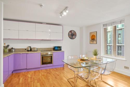 a kitchen with purple cabinets and a glass table at Mulberry Flat 5 - One bedroom 3rd floor by City Living London in London