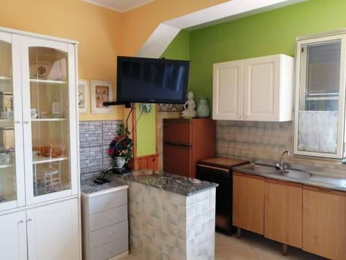 cocina con paredes verdes y TV en la pared en Appartamento Policastro - Vista mare, 