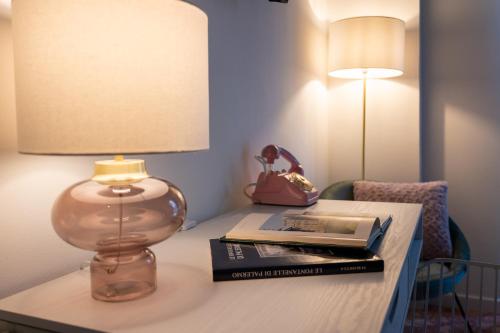 a table with a lamp and books on it at Libertà #102 - Guest House Palermo in Palermo