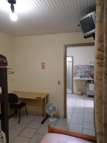um quarto com uma mesa e uma televisão na parede em Kitnets Plus em São Carlos