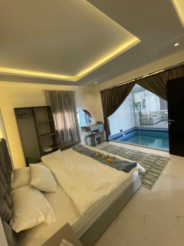 1 dormitorio con 1 cama grande y piscina en شاليهات ميلانا en Khamis Mushayt