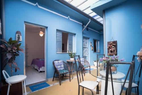 Habitación con paredes azules, mesas y sillas. en Aconchego Azul Suítes Vila Mariana, en São Paulo