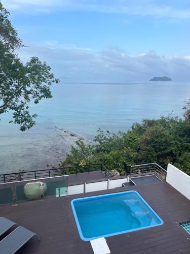 a swimming pool on a deck next to the ocean at Family Cliff House - private jacuzzi with beach views in Pathiu