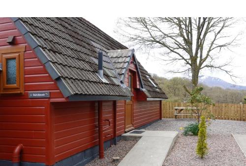 a red house with a black roof and a fence at Bunroy Park in Fort William
