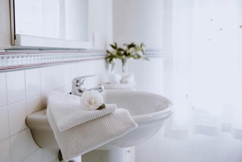 een witte badkamer met een wastafel en een handdoek bij Roero House in Magliano Alfieri
