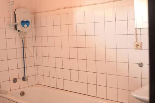 a white tiled bathroom with a tub and a toilet at Maison de 3 chambres dans un lieu apaisé au centre de Kigali in Kigali