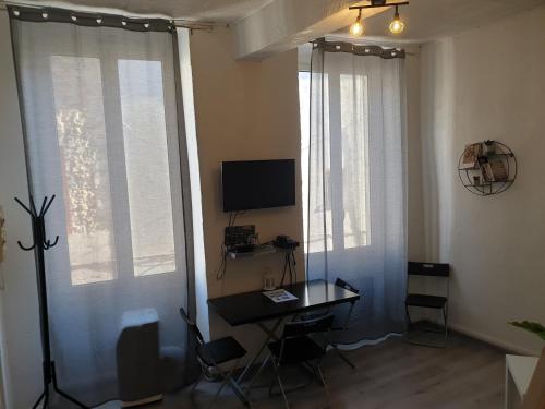 Pokój z biurkiem, telewizorem i oknami. w obiekcie Au pied du Baou w mieście Saint-Chamas