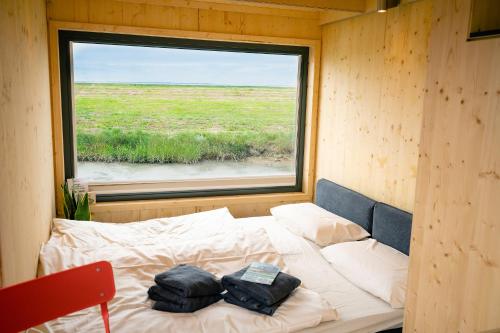 a bed in a small room with a window at Tiny House Nature 14 Zur Meerseite - Green Tiny Village Harlesiel in Carolinensiel