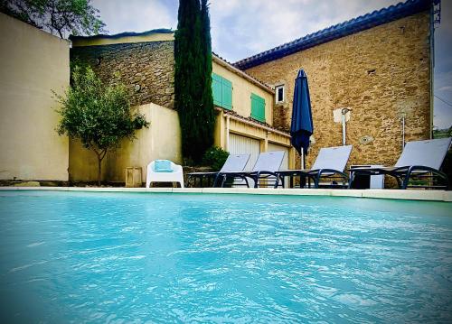 una piscina con sillas y sombrilla en LA MUSCADELLE : le calme du sud de la France, en Marseillette
