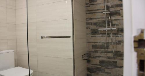 a shower with a glass door next to a toilet at Casa Mirassol in Portimão