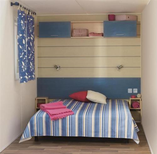 a small bedroom with a bed with pink towels on it at CAMPING LES EMBRUNS 3* in Camoël