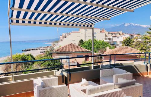 a balcony with white chairs and a view of the ocean at The Dream - Seafront Loft in Giardini Naxos