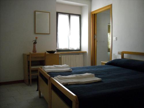 Schlafzimmer mit einem Bett mit blauer Bettwäsche und einem Fenster in der Unterkunft Affittacamere Arcobaleno in San Leo