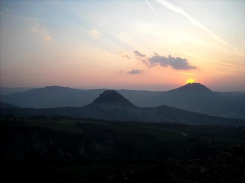 einen Sonnenuntergang über einer Bergkette mit der Sonne am Himmel in der Unterkunft Affittacamere Arcobaleno in San Leo