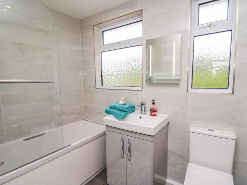a white bathroom with a sink and a tub and a toilet at Gwynant in Ystrad Meurig