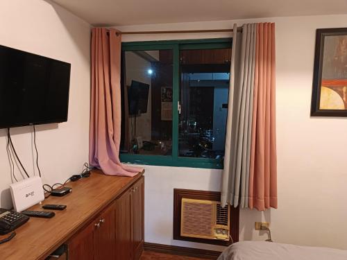 a bedroom with a desk with a television and a window at Isabelle Garden Villas 516 in Manila