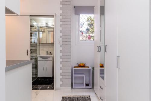 una cucina con armadi bianchi e una porta con tavolo di Casa di Rosi, Seaview studio in corfu town a Città di Corfù