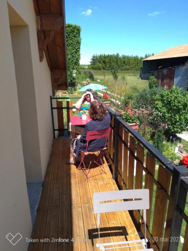 a woman sitting at a table on a balcony at Gite Au Grenier Cosy in Lor