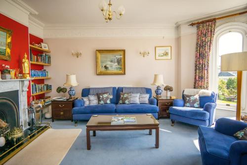 a living room with blue couches and a fireplace at Ivy House Cornwall B&B in St Austell