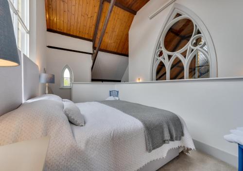 a white bedroom with a bed and a window at The Old Chapel Annexe in Nayland