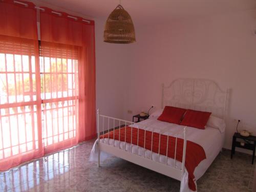 Schlafzimmer mit einem Bett mit roter Bettwäsche und Fenstern in der Unterkunft Casa El Molino in Montecorto