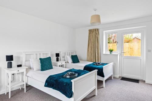 a white bedroom with two beds and a window at Number 4 - Lytton Tree Lodge, Reydon, Southwold in Reydon