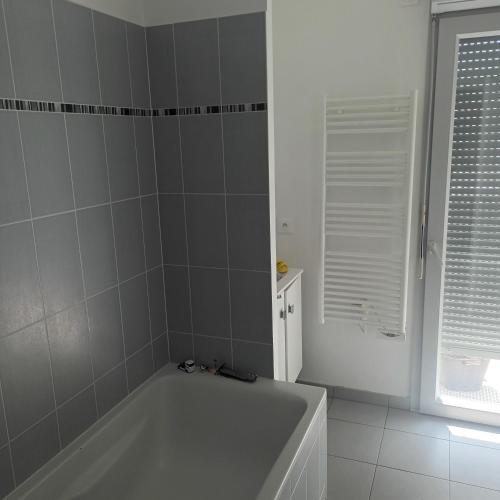 ein weißes Bad mit einer Badewanne und einem Fenster in der Unterkunft Junior in Brétigny-sur-Orge