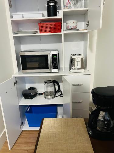 a kitchen with white shelves and a microwave at Victoria private studio suite in Victoria