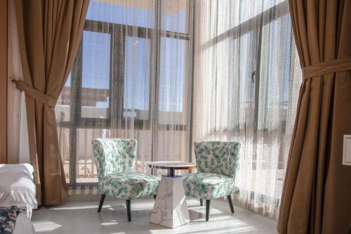 a room with two chairs and a table and large windows at AYLOL-أيلول in Qurayyah