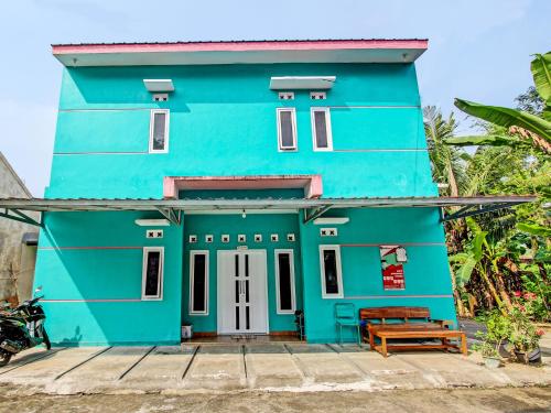 una casa azul con un banco delante en OYO 92521 Guest House Inayah Syariah en Yogyakarta