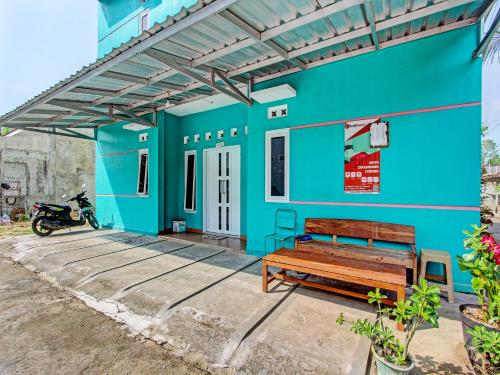 un edificio azul con un banco delante en OYO 92521 Guest House Inayah Syariah en Yogyakarta