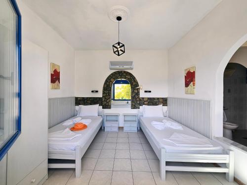 a room with two beds and a table at Pavlis Studios Ormos in Marathokampos
