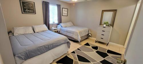 een slaapkamer met 2 bedden, een dressoir en een spiegel bij Comfy & Convenient 1BR Apartment Near Oaks Mall & Medical Center Fast WIFI in Gainesville