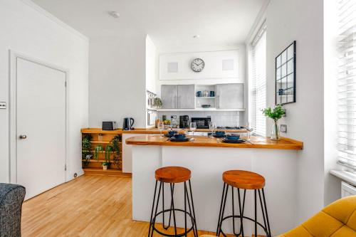 una cucina con bancone e due sgabelli di Cozy Covent Garden/Oxford Street apartment a Londra