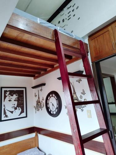 a loft bed in a room with a clock on the wall at Isabelle Garden Villas 828 in Manila