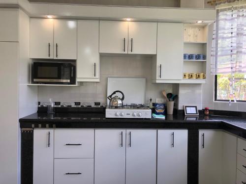 a kitchen with white cabinets and a black counter top at Family house/casa de Familia 3 bedroom 3 bath in Baños