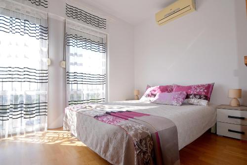 a white bedroom with a large bed and windows at Lungo Mare Apartment with Terrace in Pula